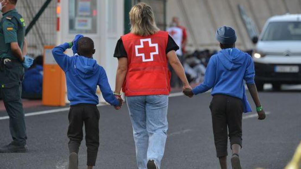Una trabajadora de Cruz Roja escolta a dos menores inmigrantes de Canarias, en una foto de archivo.