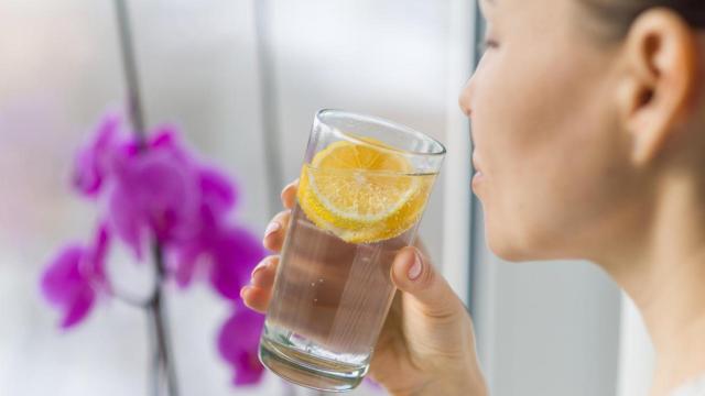 Mujer bebiendo agua con limón.