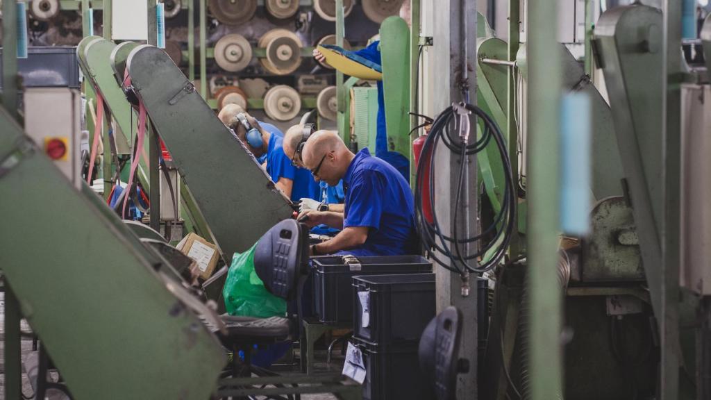 Varios operarios pulen los mangos de los cuchillos recién remachados.