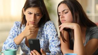 Amigas mirando el móvil con cara de preocupación.