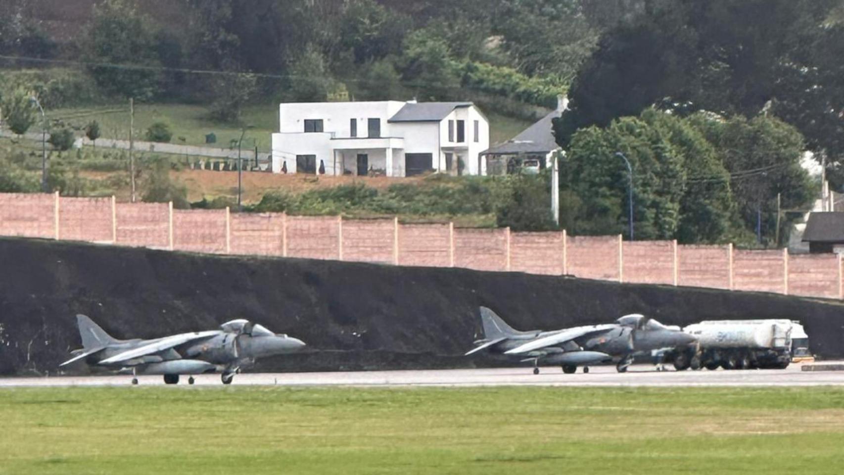 Dos aviones de la Armada aterrizan en Alvedro, con una vivienda al fondo.