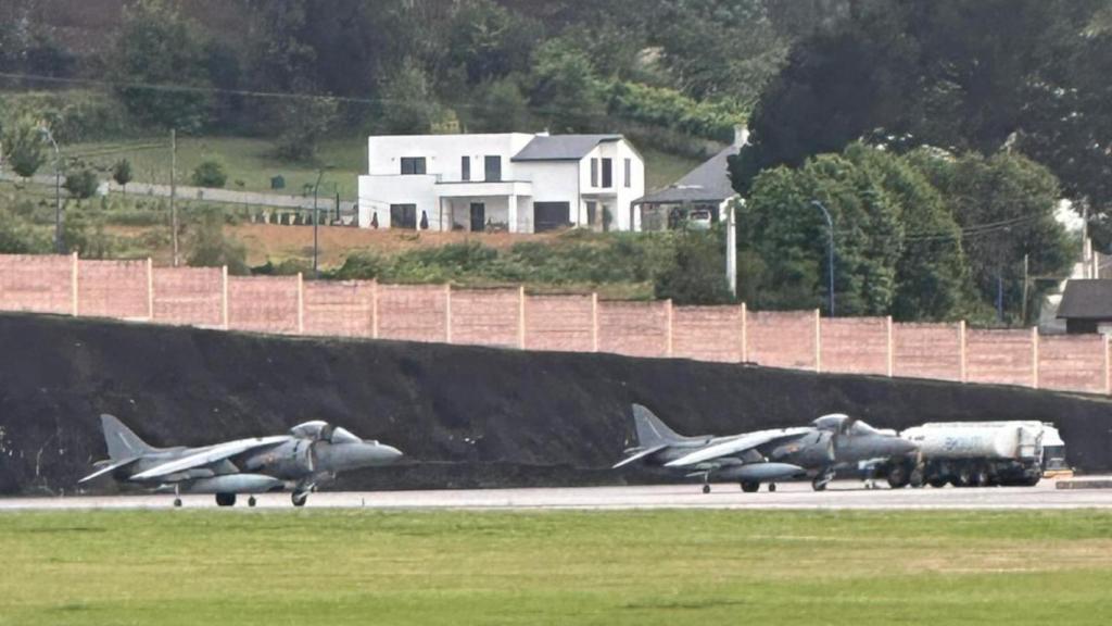 Dos aviones de la Armada aterrizan en Alvedro, con una vivienda al fondo.