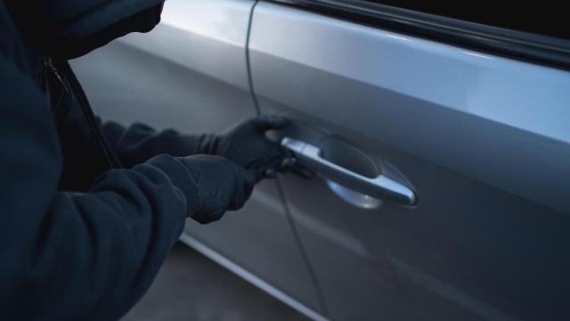 Imagen de archivo de un ladrón intentando robar un coche.