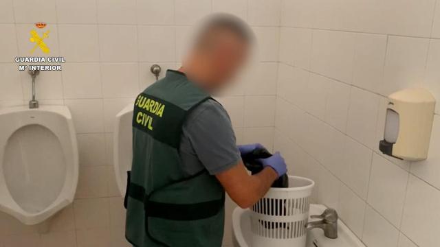 Un agente registrando la papelera donde estaba el móvil.