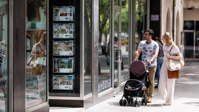 Dos personas observan los anuncios de viviendas en venta en una inmobiliaria.