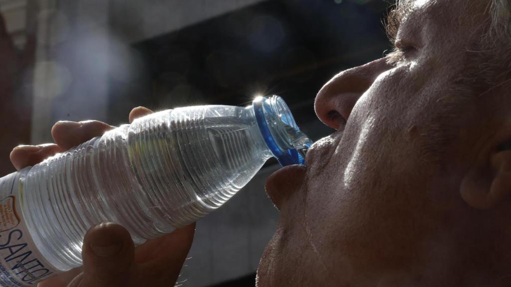 Un señor se refresca bebiendo una botella de agua.