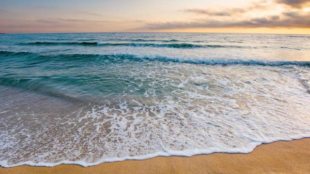 Playa con agua cristalina y atardecer.