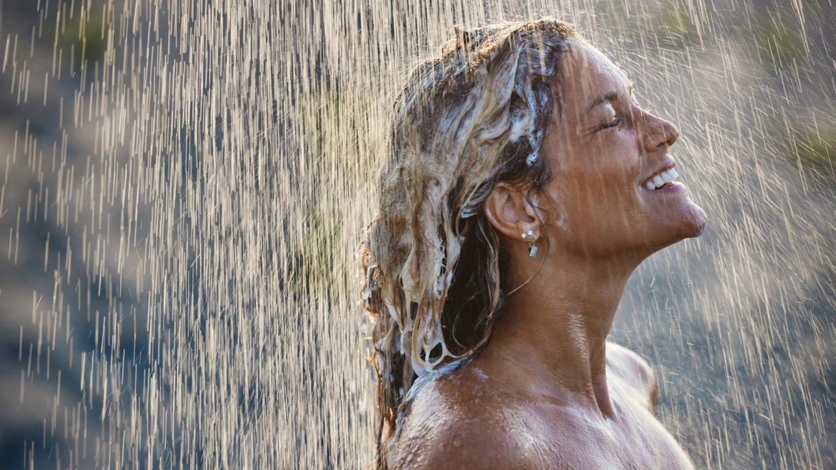 Mujer lavándose el pelo al aire libre.