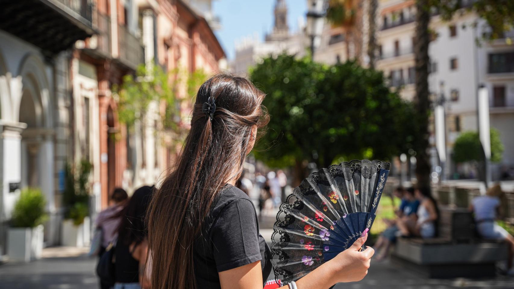 Una mujer se abanica en la calle.