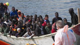 A canoe lands on the coast of Arguineguín with around fifty people.