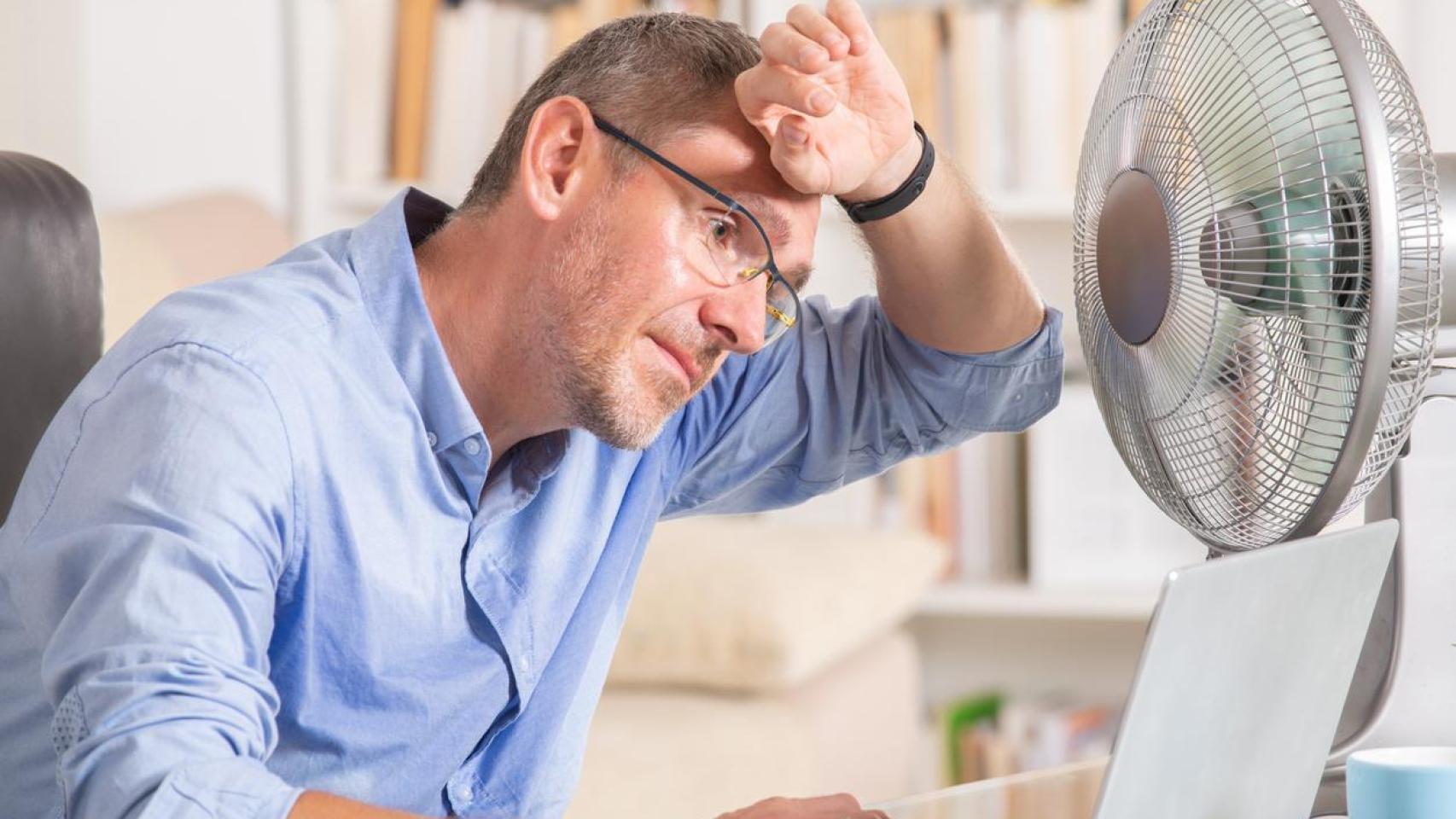 Imagen de un hombre pasando calor en la oficina.