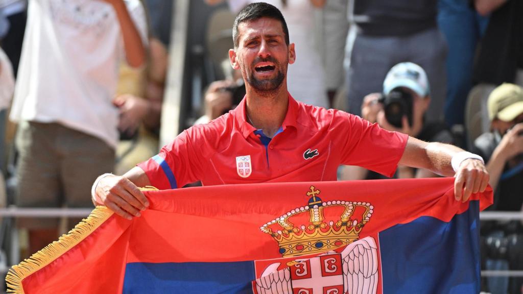 Novak Djokovic luce la bandera de Serbia al término de un partido.