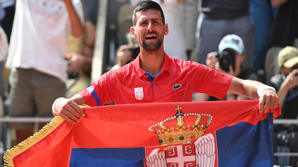 Novak Djokovic luce la bandera de Serbia al término de un partido.