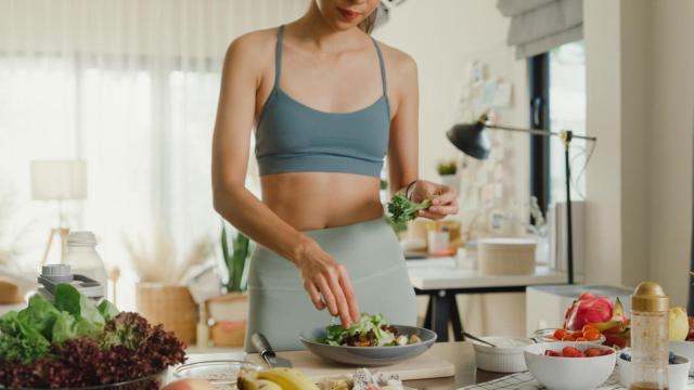 Mujer en ropa de deporte preparándose una ensalada.