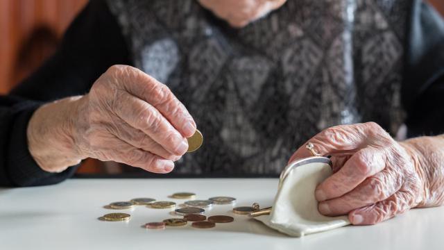 Una anciana contando dinero de su monedero.