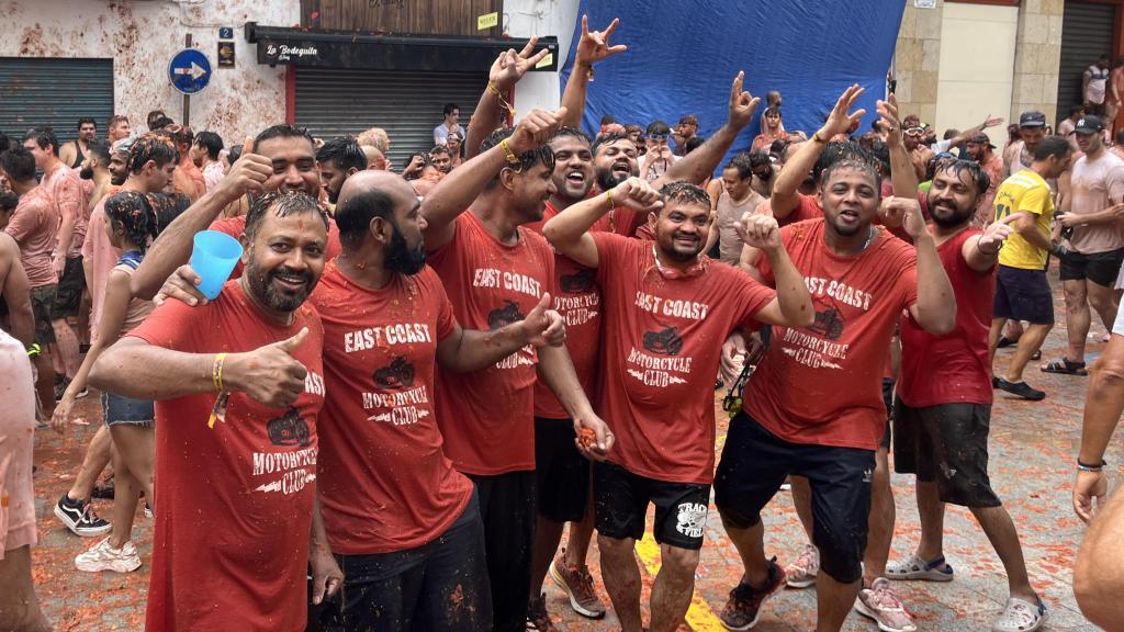 Asistentes a la Tomatina de Buñol 2024 se toman una fotografía tras el paso de los camiones. Raquel Granell