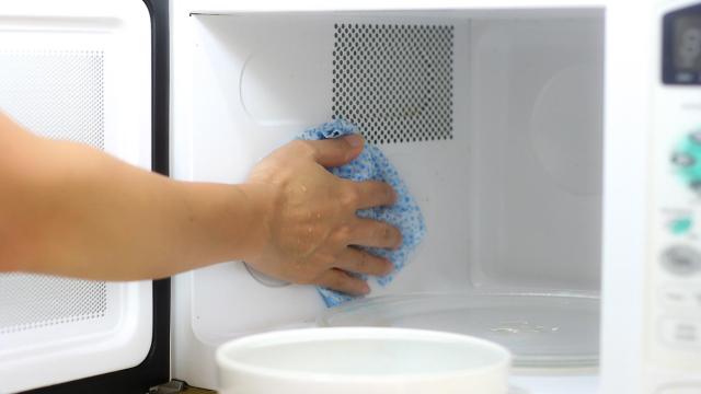 Una persona limpiando el microondas.