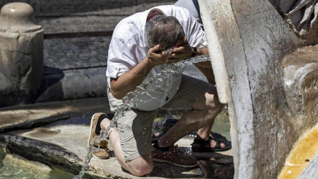Un turista se refresca durante un día de calor en Sevilla.