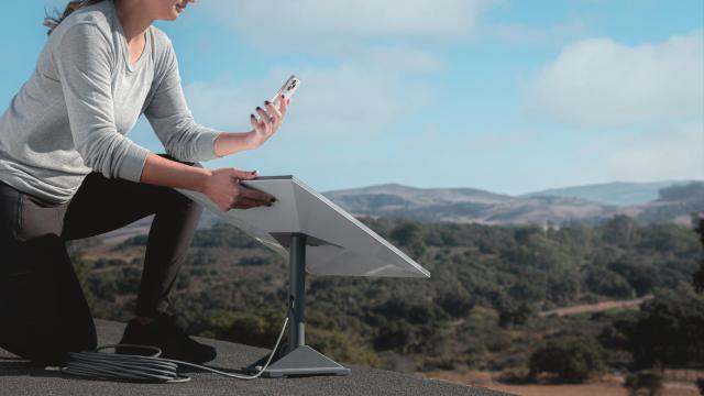 Una persona con un iPhone junto con una antena Starlink.