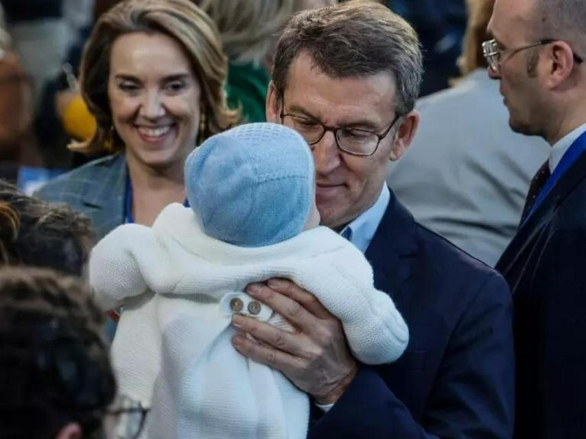 Alberto Núñez Feijóo bromea con un niño, con Cuca Gamarra a su espalda.