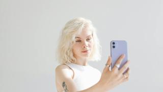 Mujer joven con pelo blanco posando con el móvil