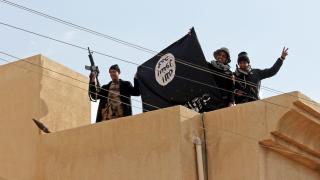 Iraqi soldiers display an Islamic State flag.