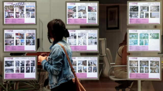 Una persona pasa frente al escaparate de una agencia inmobiliaria.