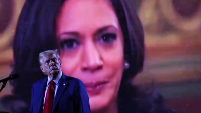 El candidato republicano Donald Trump frente a una pantalla donde se proyecta una imagen de su oponente, Kamala Harris, durante un mitin en Huntington Place.