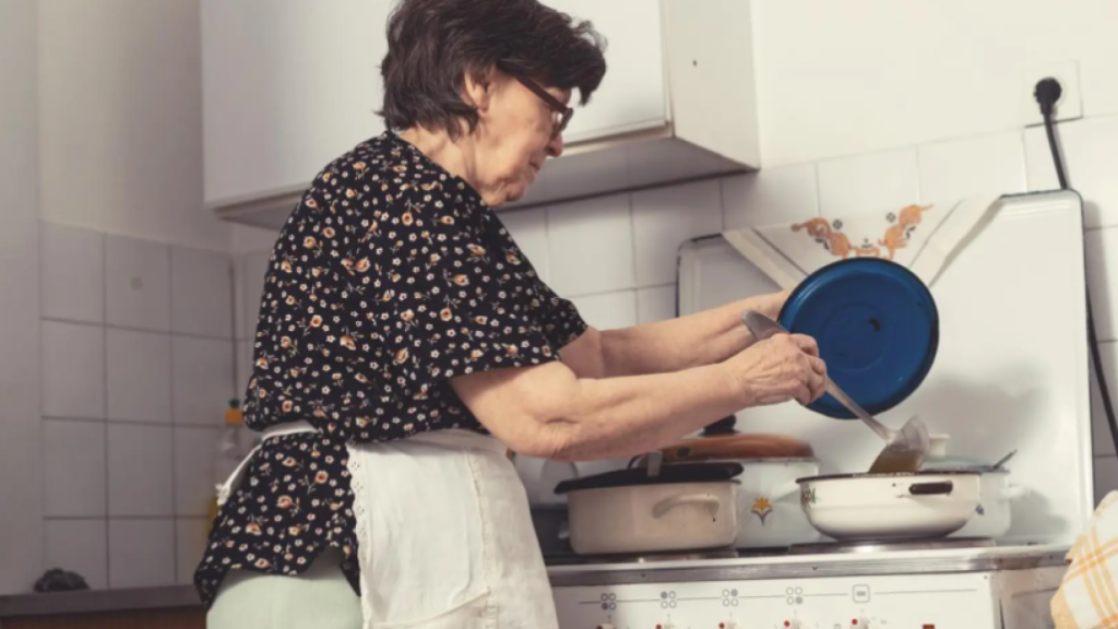 Imagen de una anciana cocinando.