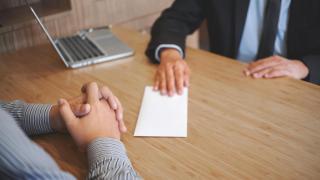 Fotografía de un hombre entregando su carta de renuncia al jefe de su departamento.