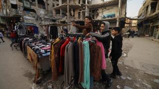 Firas, de 15 años, un vendedor ambulante, bromea con sus amigos mientras está de pie junto a su puesto en el mercado callejero, después de la derrocación del presidente Bashar al-Assad, en Douma, Siria, el 2 de enero de 2025.