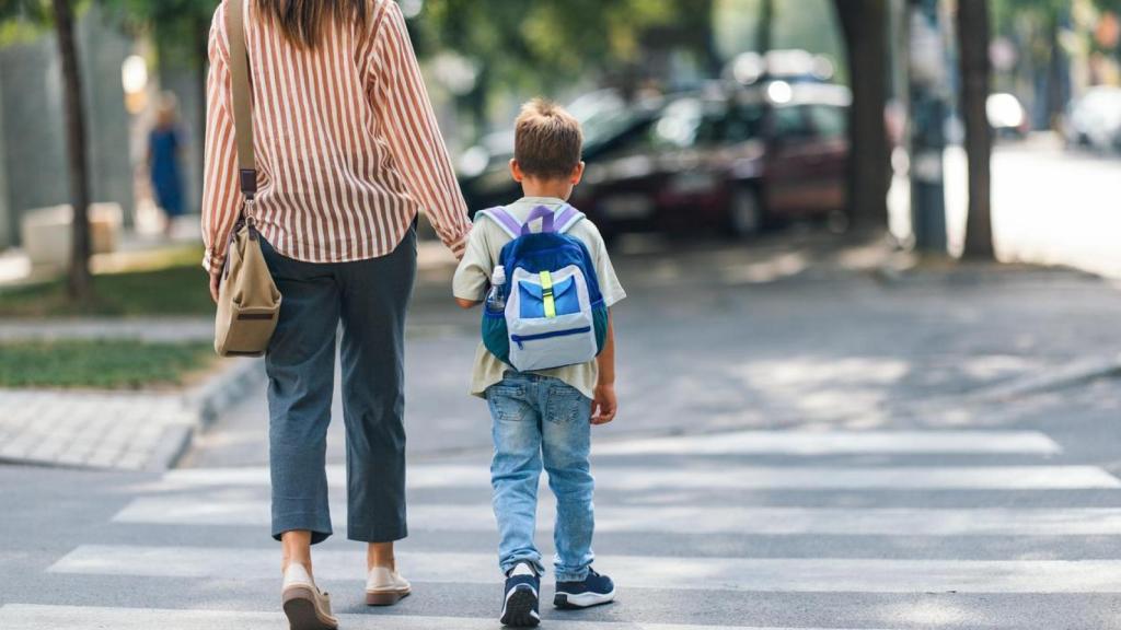 Imagen de recurso de una mujer y un niño de camino a una escuela.