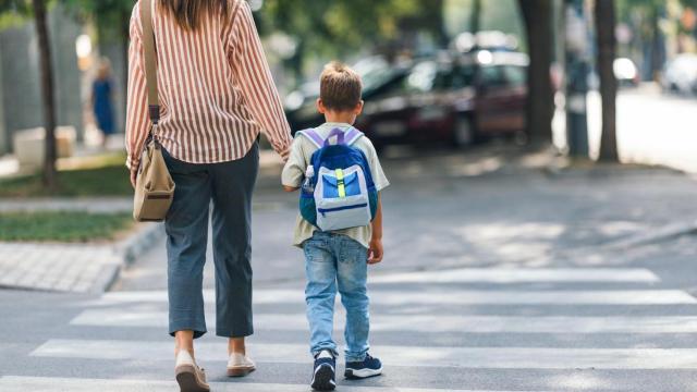 Imagen de recurso de una mujer y un niño de camino a una escuela.