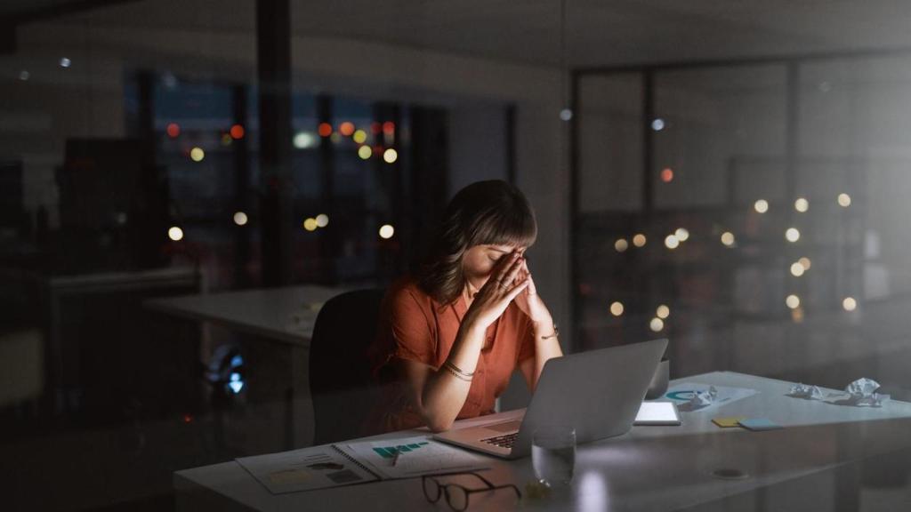Mujer con aspecto cansado en su mesa de trabajo.