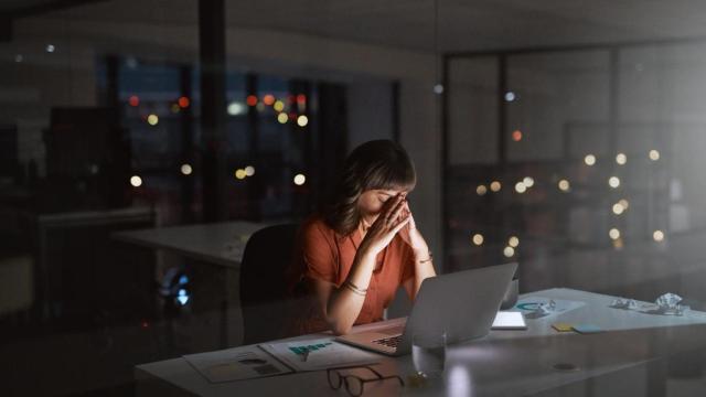 Mujer con aspecto cansado en su mesa de trabajo.