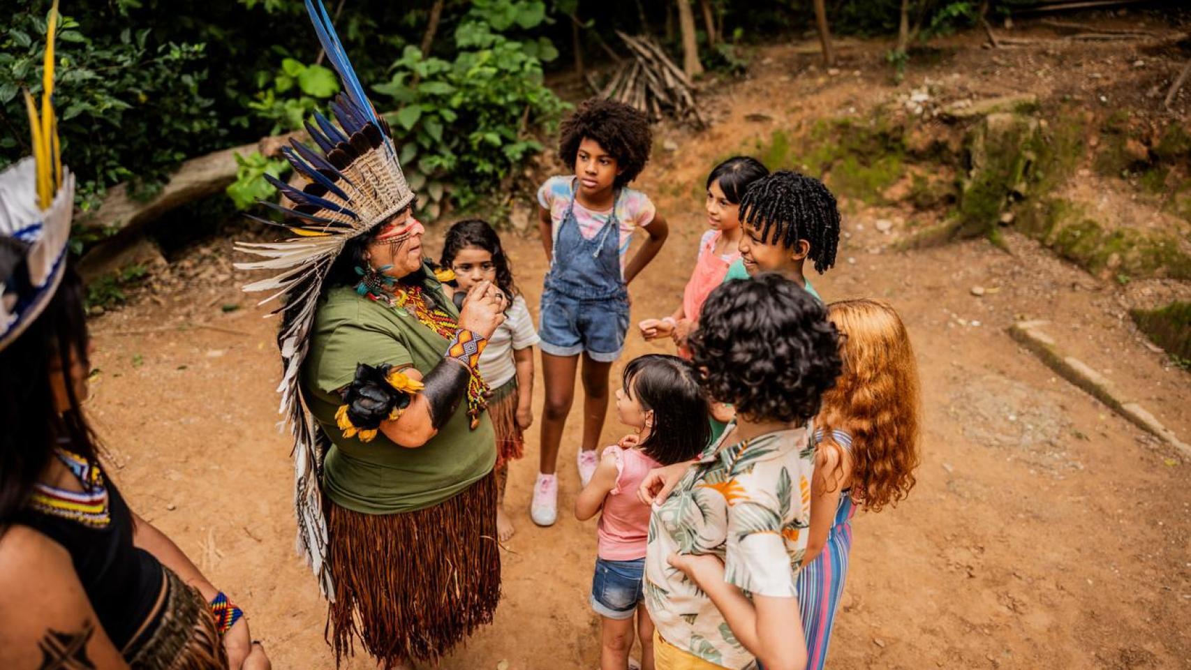 Una mujer indígena habla con niños de una escuela durante una excursión en Brasil.