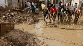 Un grupo de voluntarios tratando de retirar el lodo de una calle de Masanasa.
