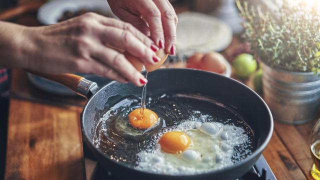 Una persona fríe huevos en una sartén con aceite