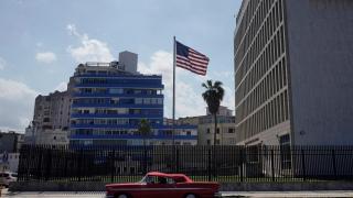 A classic car used for sightseeing tours of the city drives past the United States Embassy in Havana, Cuba.