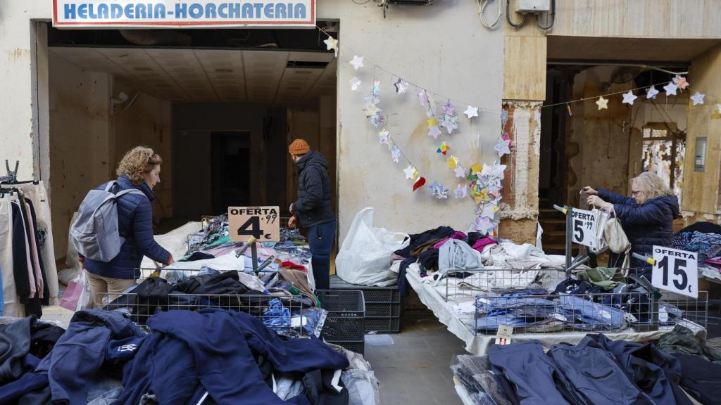 Varias personas recorren el mercadillo instalado en las calles de Paiporta. Efe / Ana Escobar