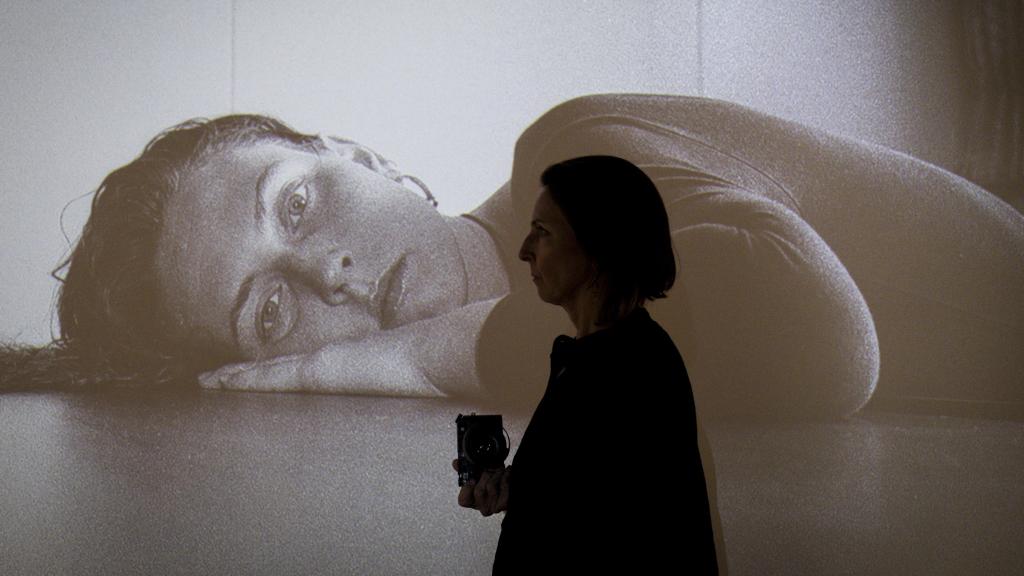 Ana Nance posa frente a un autorretrato de su exposición 'Around the world'. Fotografía realizada con Leica Q3 43.