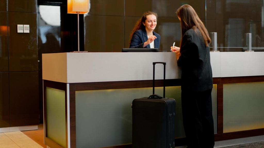Una clienta en la recepción de un hotel rellenando un documento.