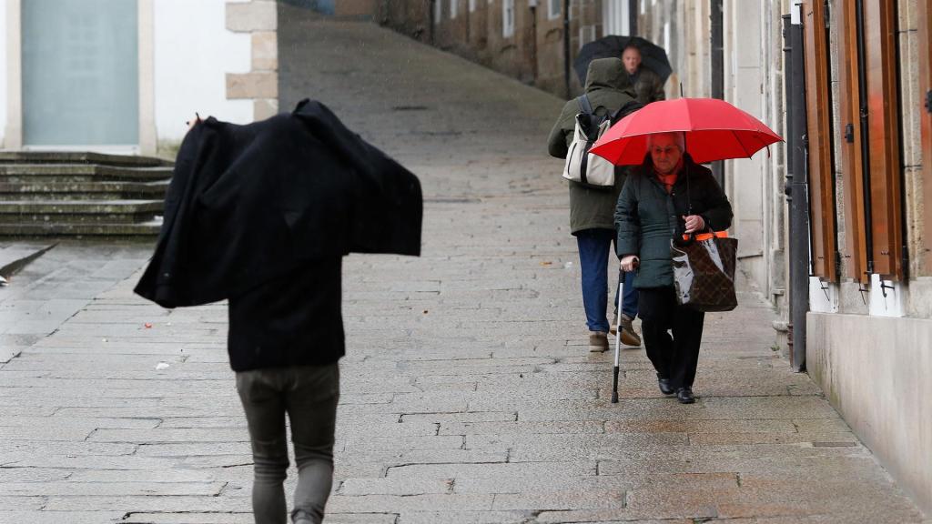 Varias personas caminando bajo la lluvia.