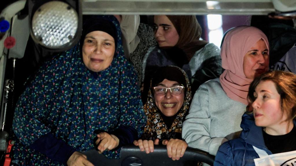 Algunos de los rehenes palestinos sonríen en el autobús una vez liberados.