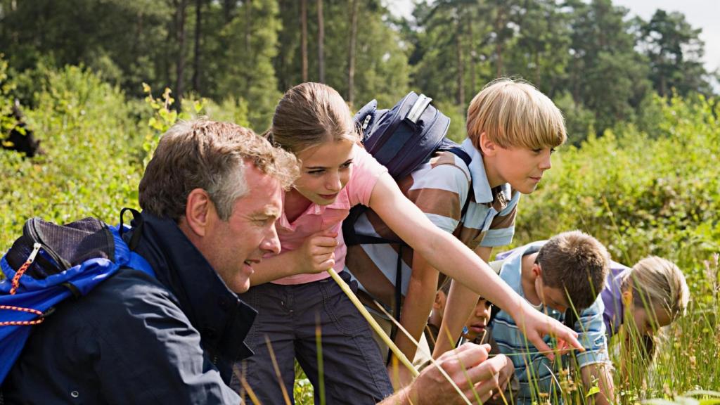 Un profesor explica a los alumnos las propiedades de las plantas en la sierra.