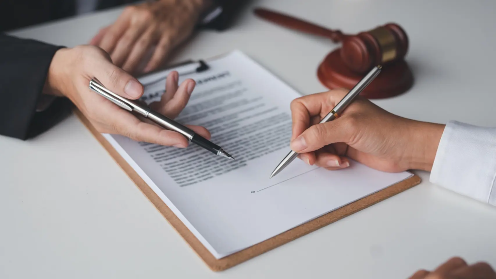 Dos personas firmando unos documentos.
