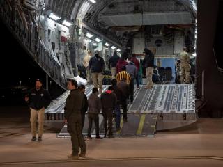Agentes fronterizos montan en un avión de la Fuerza Aérea a una cuerda de inmigrantes detenidos para deportarlos.