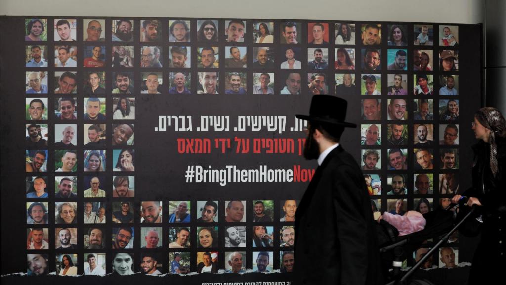 Un judío ultraortodoxo observa un  mural en Tel Aviv con los rostros de los rehenes tomados por Hamás en los ataques del 7 de octubre.