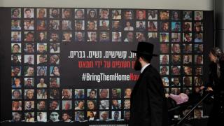 Un judío ultraortodoxo observa un  mural en Tel Aviv con los rostros de los rehenes tomados por Hamás en los ataques del 7 de octubre.