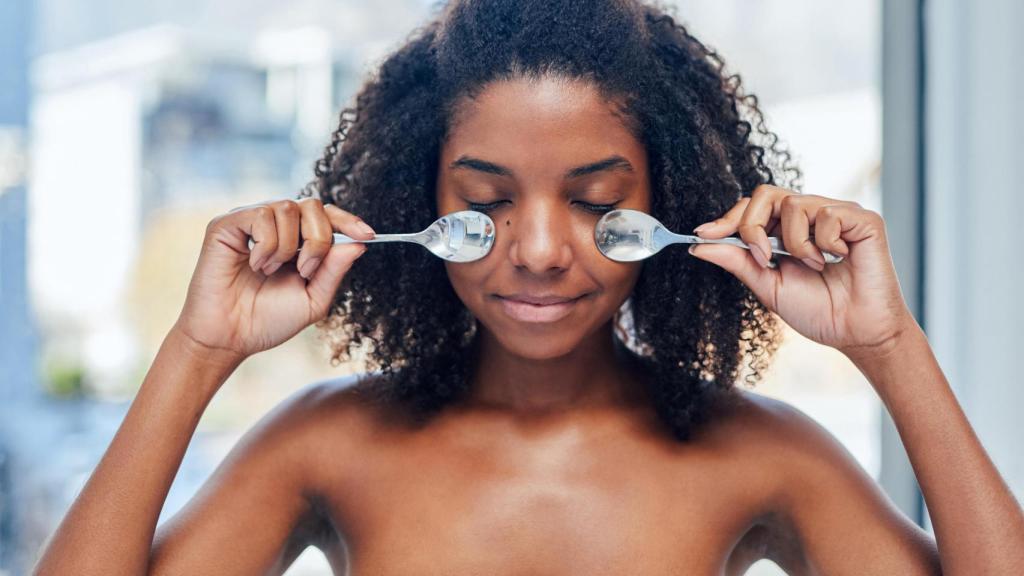 Mujer con dos cucharas en el rostro.